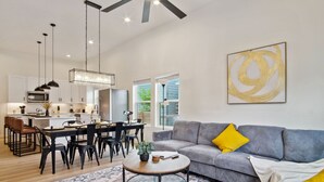 A modern living room with a grey sofa, a round coffee table, and a dining area with a black table and chairs. - Skyline Retreat 3br-3ba w Stunning Views Near DT (San Antonio)