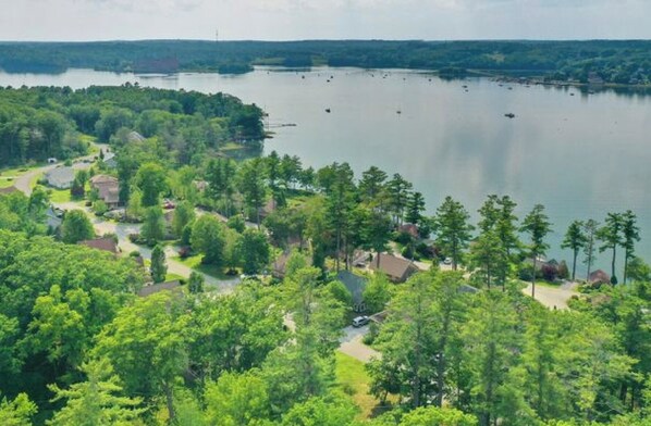 A lakeside residential area with houses surrounded by dense trees and a calm lake. - Charming Sheepscot Overlook Cottage (Edgecomb)