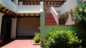 Un edificio de varios niveles con escaleras, zona de estar al aire libre y plantas en macetas.
