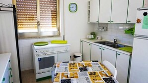 A compact kitchen with a stove, sink, and white cabinets. - Casa Caretta Caretta a San Lorenzo (Noto)