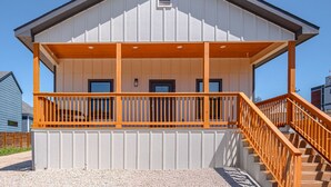 A two-story building with a covered porch and a staircase. - 3br-2ba Cityscape Haven With Panoramic Tower View (San Antonio)