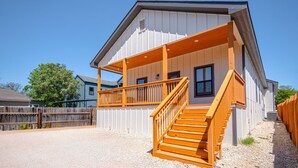 A two-story building with a covered porch and wooden stairs. - 3br-2ba Cityscape Haven With Panoramic Tower View (San Antonio)