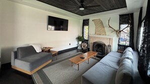 A living room with a fireplace, sofas, a coffee table, and a ceiling fan. - Welcome to the Raven Rose - A Chic, Newly Renovated 2BD/1BA Home (Logan)