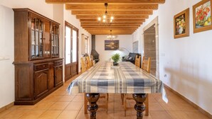 Un comedor con una mesa larga, armarios de madera y una lámpara de araña.
