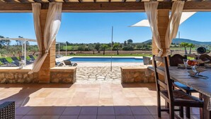Un patio al aire libre con piscina, suelo de piedra y vistas al campo.