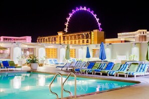 A pool area with lounge chairs and a Ferris wheel in the background. - StripViewSuites at Platinum (Las Vegas)