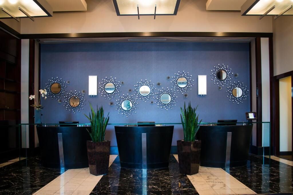 A reception area with a dark blue wall, multiple mirrors, and a glass counter.