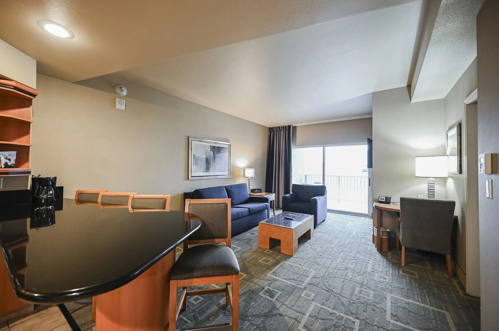 Une chambre d’hôtel équipée d’une table à manger, d’un canapé, de chaises, d’une petite table basse et d’un balcon avec vue.