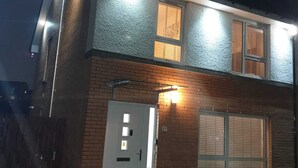 Un bâtiment à deux étages avec une porte blanche, une petite fenêtre avec des stores et le numéro « 27 » peint sur le mur.