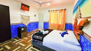 A hotel room with a bed, a ceiling fan, a television, a door, and a window with curtains. - Hotel Maya Dreams (Bacalar)