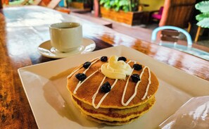 A breakfast plate with pancakes, syrup, and berries.