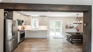 Una cocina moderna con electrodomésticos de acero inoxidable, armarios blancos y suelo de madera.