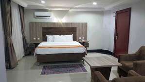 Habitación de hotel con cama, mesita de noche, silla y un pequeño escritorio.