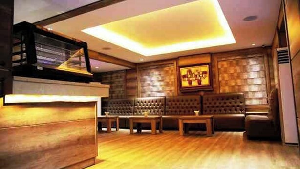 Un interior moderno con un mostrador de recepción de madera, asientos de cuero y un amplio techo iluminado.
