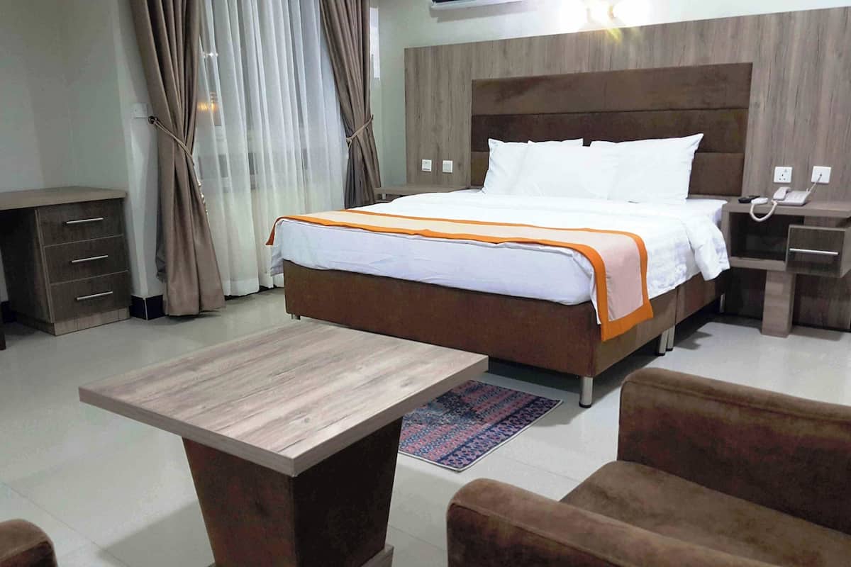 A hotel room with a bed, bedside tables, a desk, and a chair.