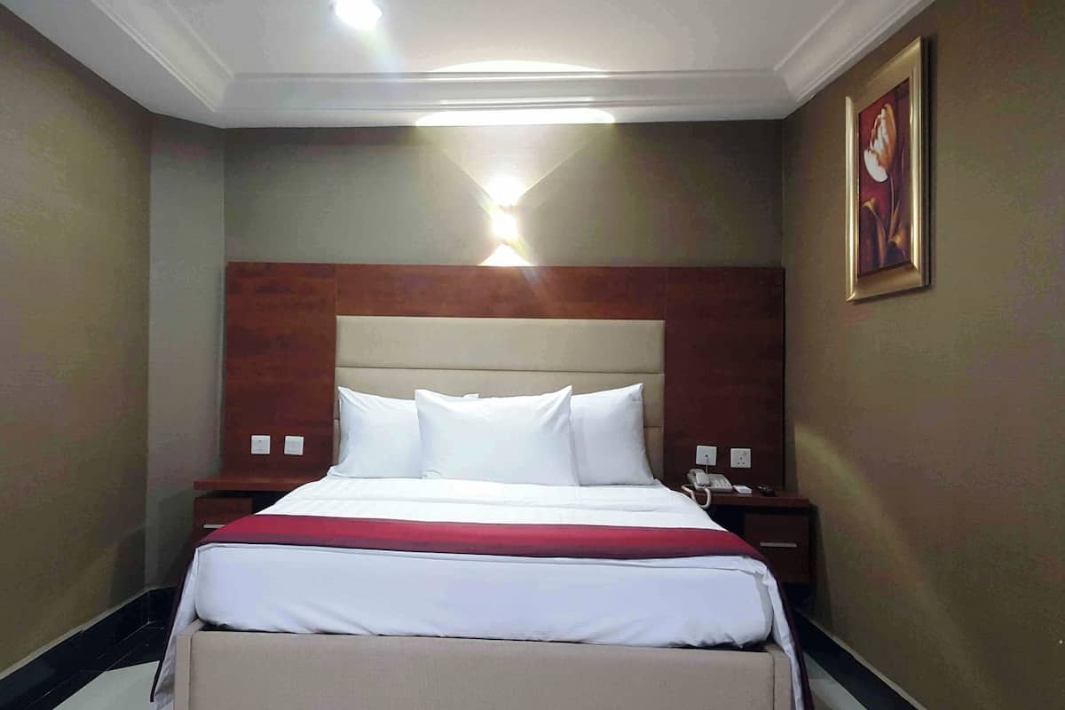 A hotel room with a bed, a nightstand, a telephone, and a painting on the wall.