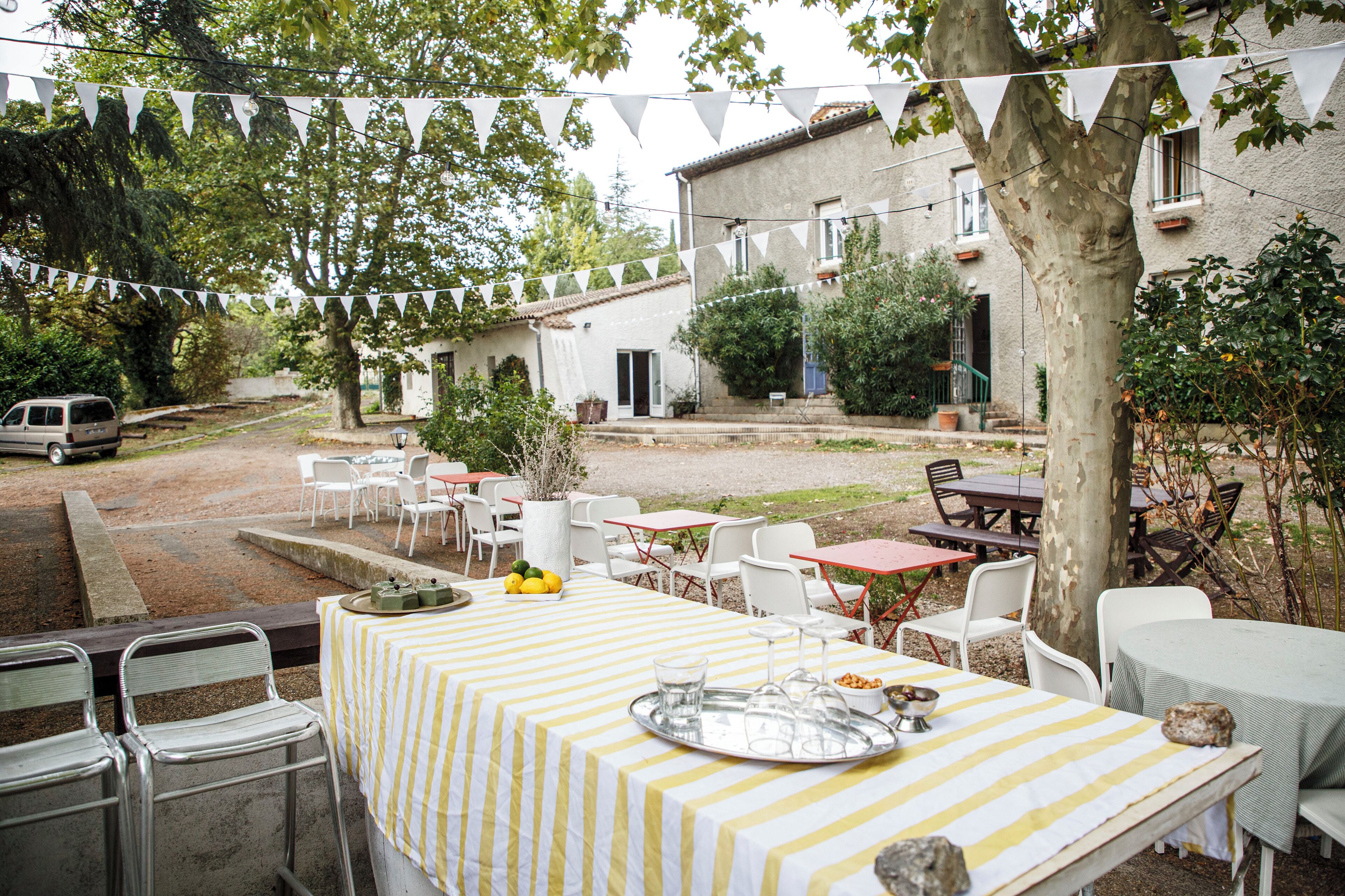 An outdoor patio area with tables and chairs, a car parked nearby, and a building in the background.