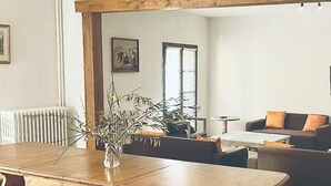 A spacious living area with a wooden dining table, benches, and a green upholstered chair. - Domaine Castelnaut gîte et château (Laroque-de-Fa)