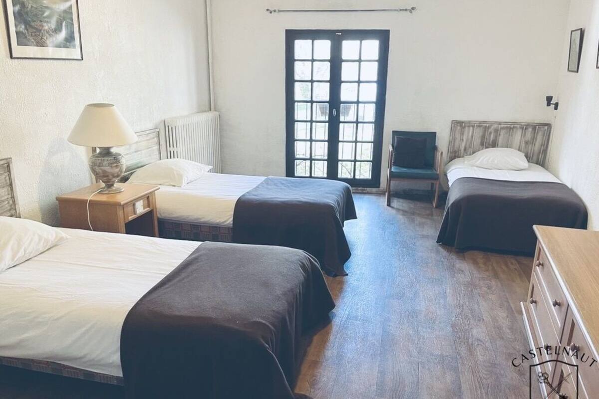 A room with three beds, a radiator, a chair, and a wooden dresser.
