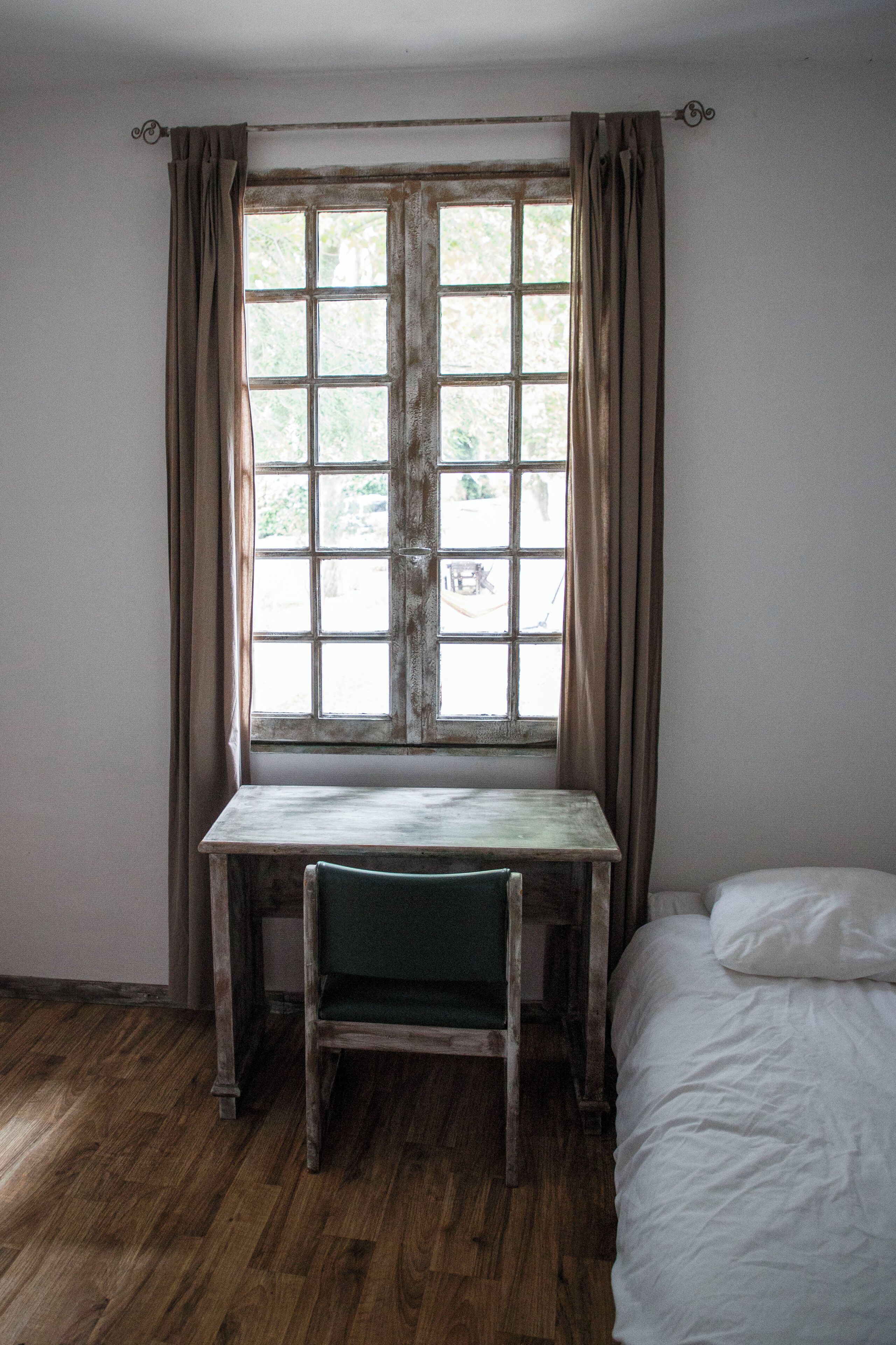 A room with a wooden desk, a chair, and a bed.