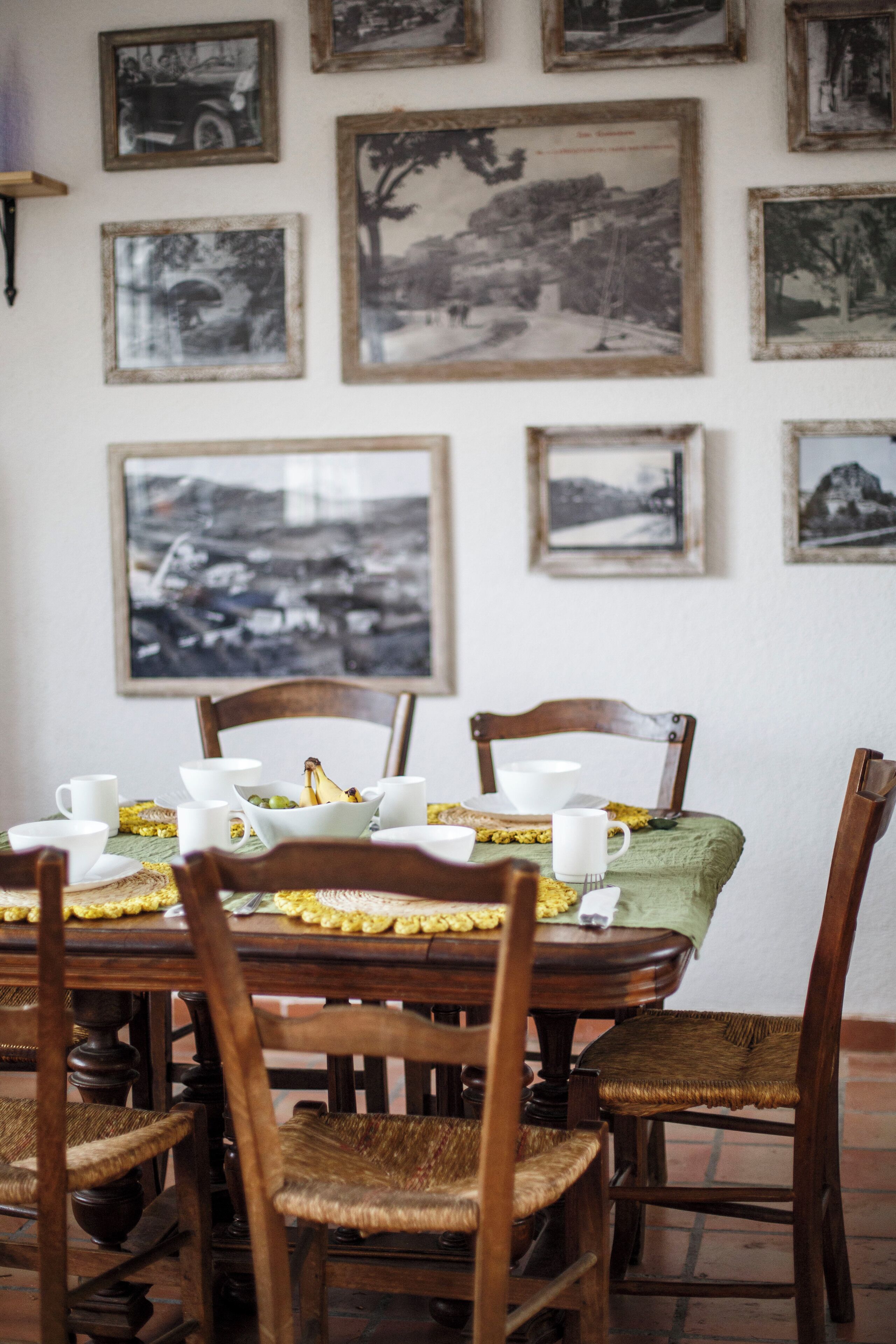 Comedor con mesa de madera dispuesta para cuatro personas, rodeado de sillas de mimbre.