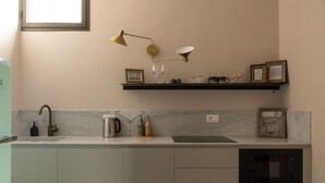 A modern kitchen with a marble countertop, a built-in oven, and a wall-mounted shelf with decorative items.