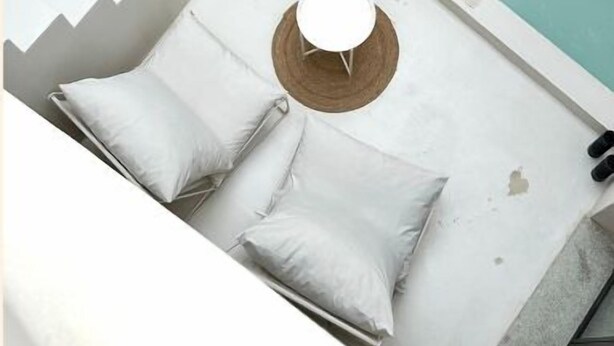 A modern bathroom with a bathtub, a small round table, and a bench with pillows.