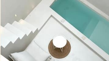 Un bagno moderno con una vasca, un tavolino rotondo e una panca con dei cuscini.