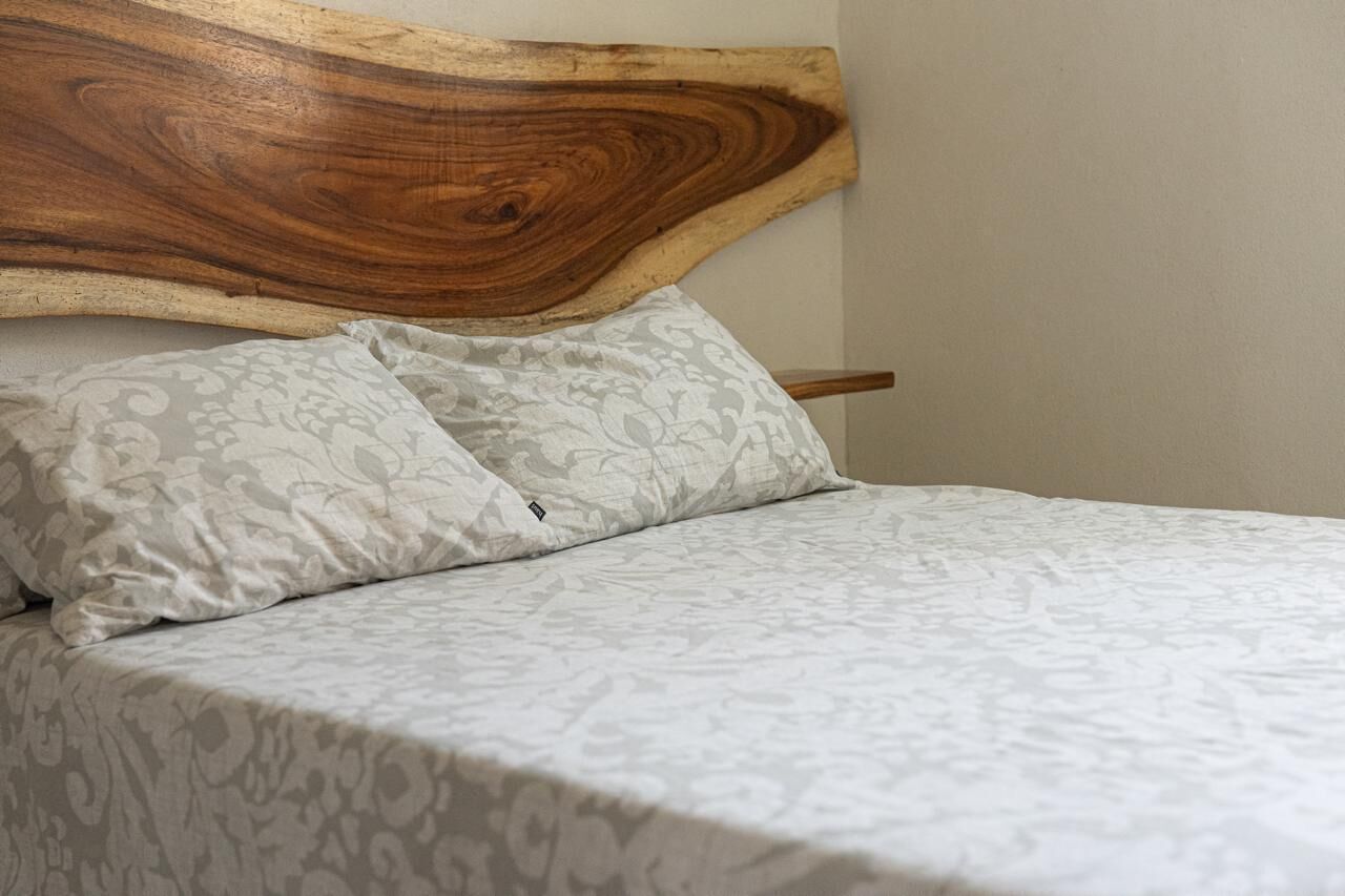 Een bed met een houten hoofdbord en beddengoed met een patroon.