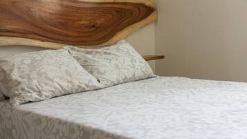 Een bed met een houten hoofdbord en beddengoed met een patroon.