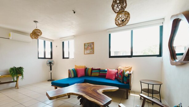 Una sala de estar moderna con un sofá seccional azul, una mesa de centro de madera y una mesa redonda.