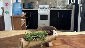 Una cocina moderna con estufa a gas, horno y microondas. Cuenta con dispensador de agua, estante de madera con utensilios de cocina y una jarra de agua grande.