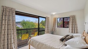 Ein Schlafzimmer mit einem großen Bett, einem Fenster mit Vorhängen und einem Balkon mit einem Stuhl.