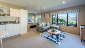 Un salon moderne avec un canapé, une table basse et une vue sur un paysage montagneux, visible à travers de grandes fenêtres.