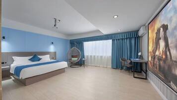 Habitación de hotel con cama, una silla colgante, un escritorio y un cuadro grande en la pared.