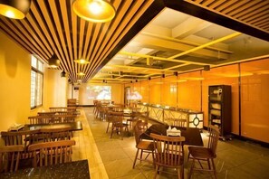 Ein Restaurant mit Holztischen und -stühlen, einer Bar und einer Projektionsleinwand an der Wand.