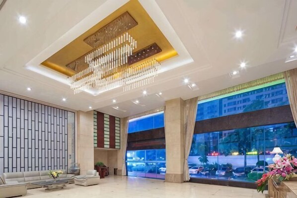 Un vestíbulo amplio con candelabro, ventanas grandes y una zona de estar.