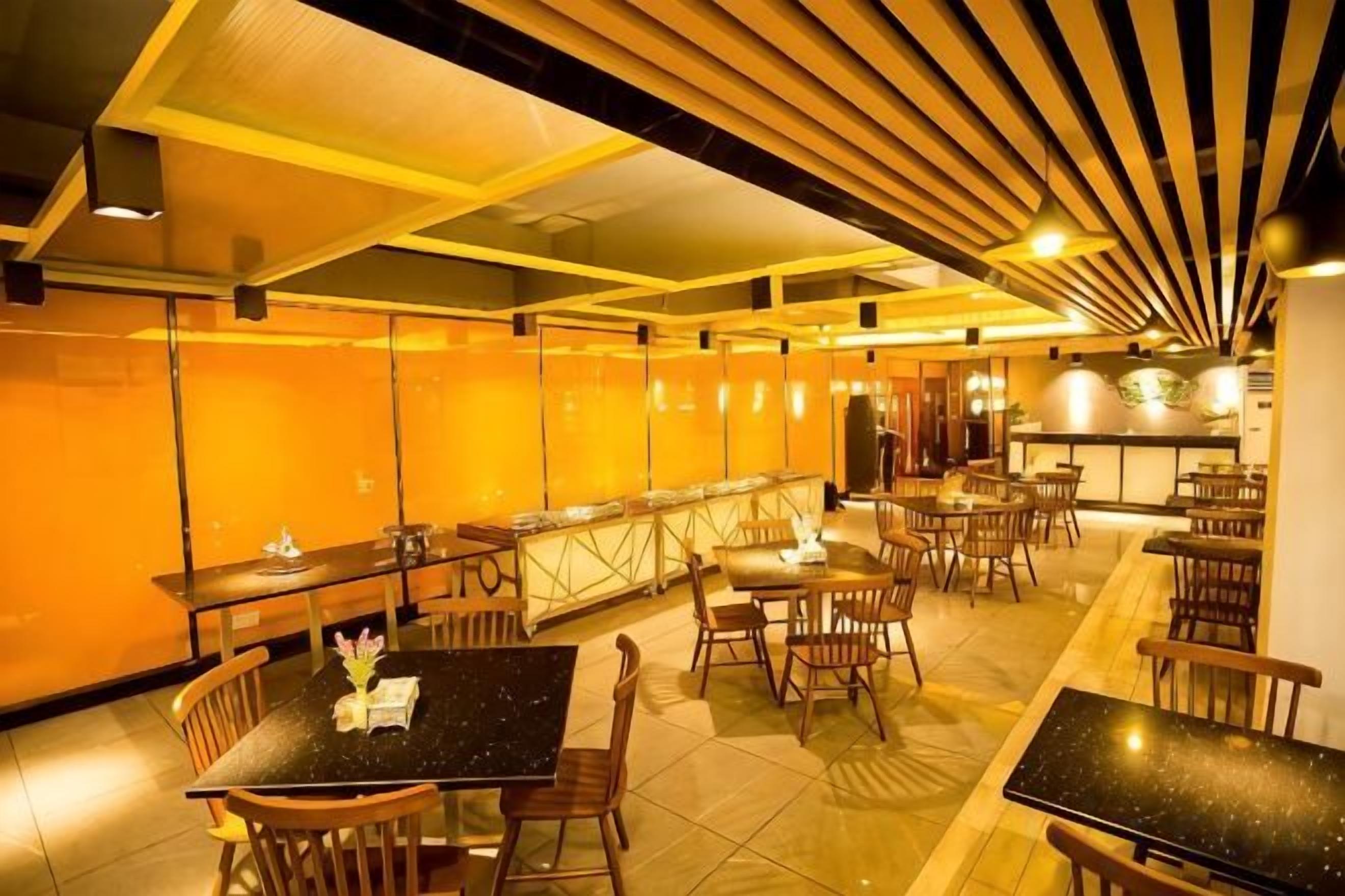 A restaurant with multiple tables and chairs, a bar area, and a high ceiling with wooden slats.