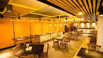 A restaurant with multiple tables and chairs, a bar area, and a high ceiling with wooden slats.