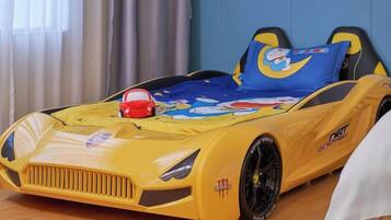 A child's bed with a cartoon car design, a pillow with a cartoon character, and a toy car.