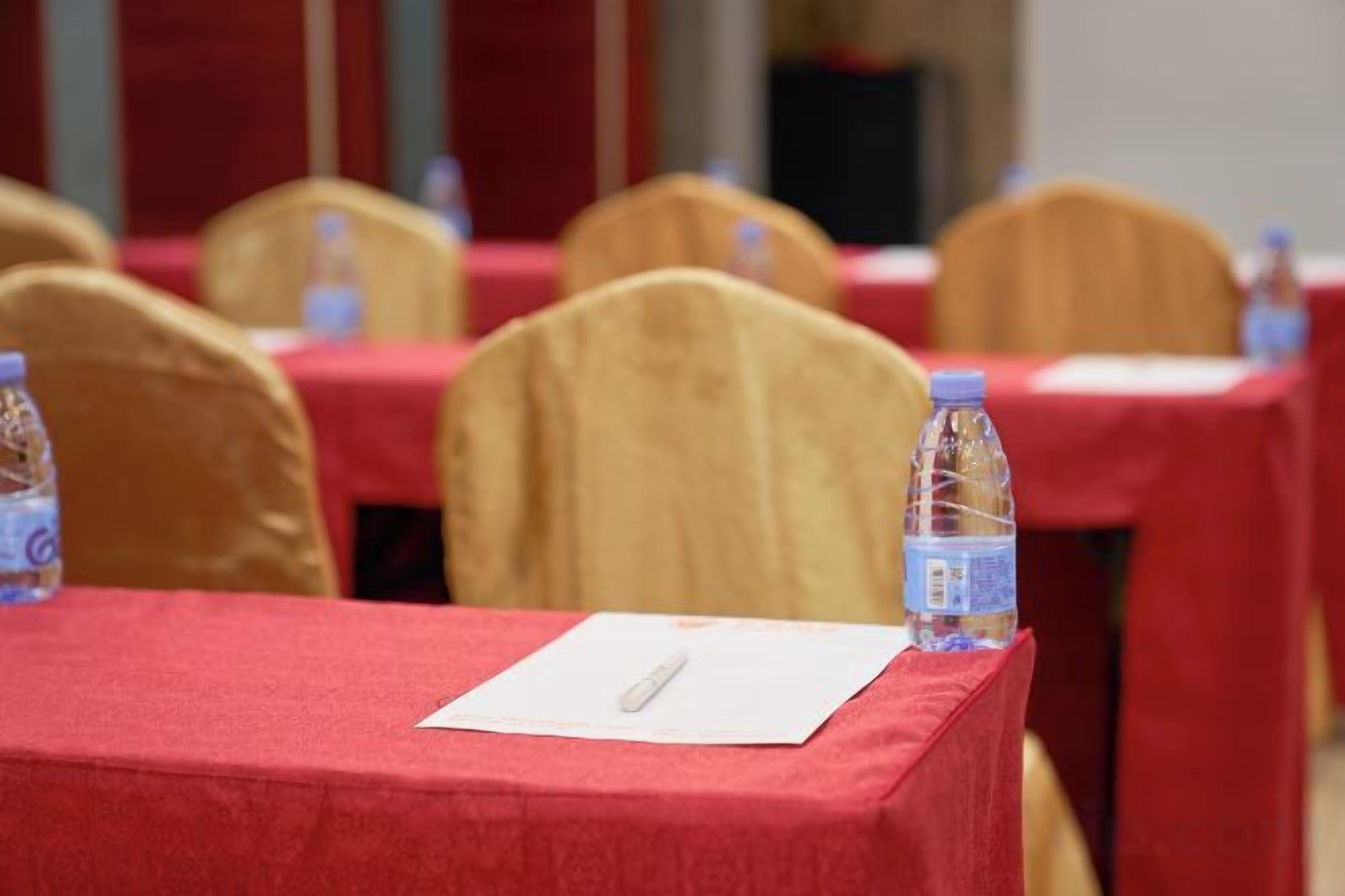 A conference table with a red tablecloth, a notepad, and a water bottle.