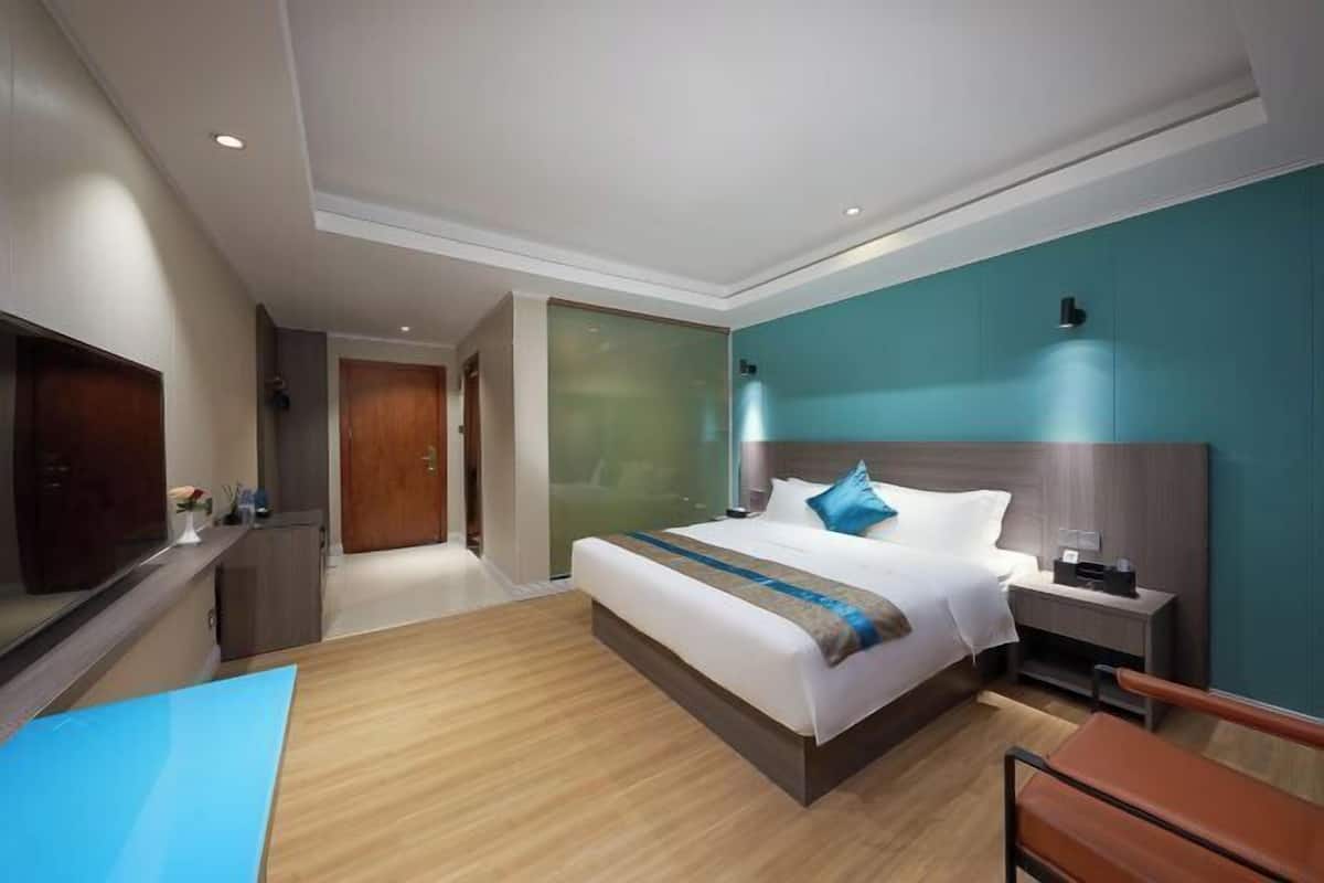 Una habitación de hotel moderna con una cama grande, mesitas de noche, un escritorio y un televisor.