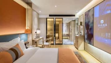 A modern hotel room with a large bed, a desk, and a television screen.