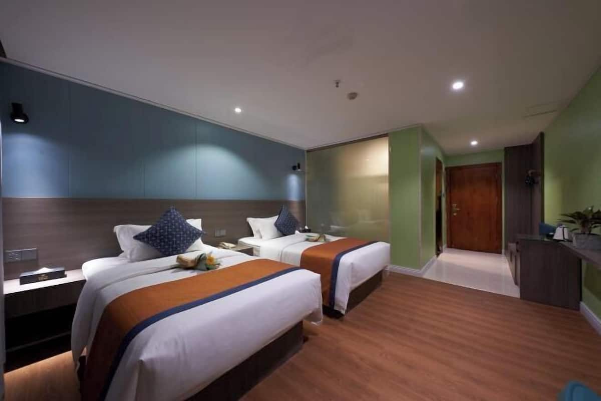 Una habitación de hotel con dos camas, un escritorio y una pequeña cocina.