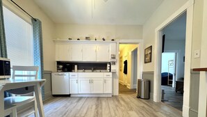 A compact kitchen with white cabinets, a dishwasher, and a dining area with a white table and chairs. - 2-bedroom apartment in fabulous Somerville with AC, WiFi and off street parking (Somerville)