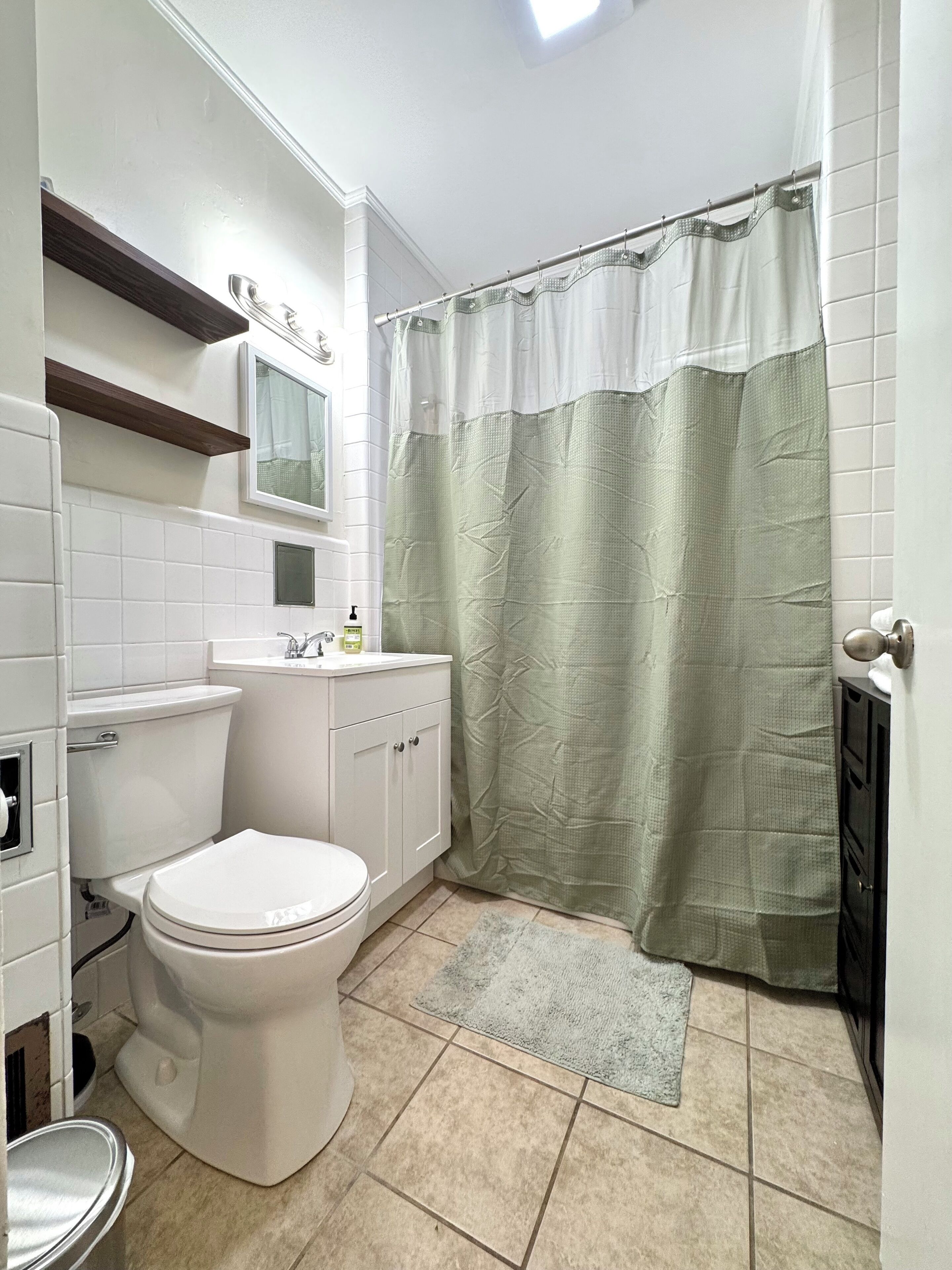 Une salle de bain équipée de toilettes, d’un lavabo, d’un miroir et d’un rideau de douche.