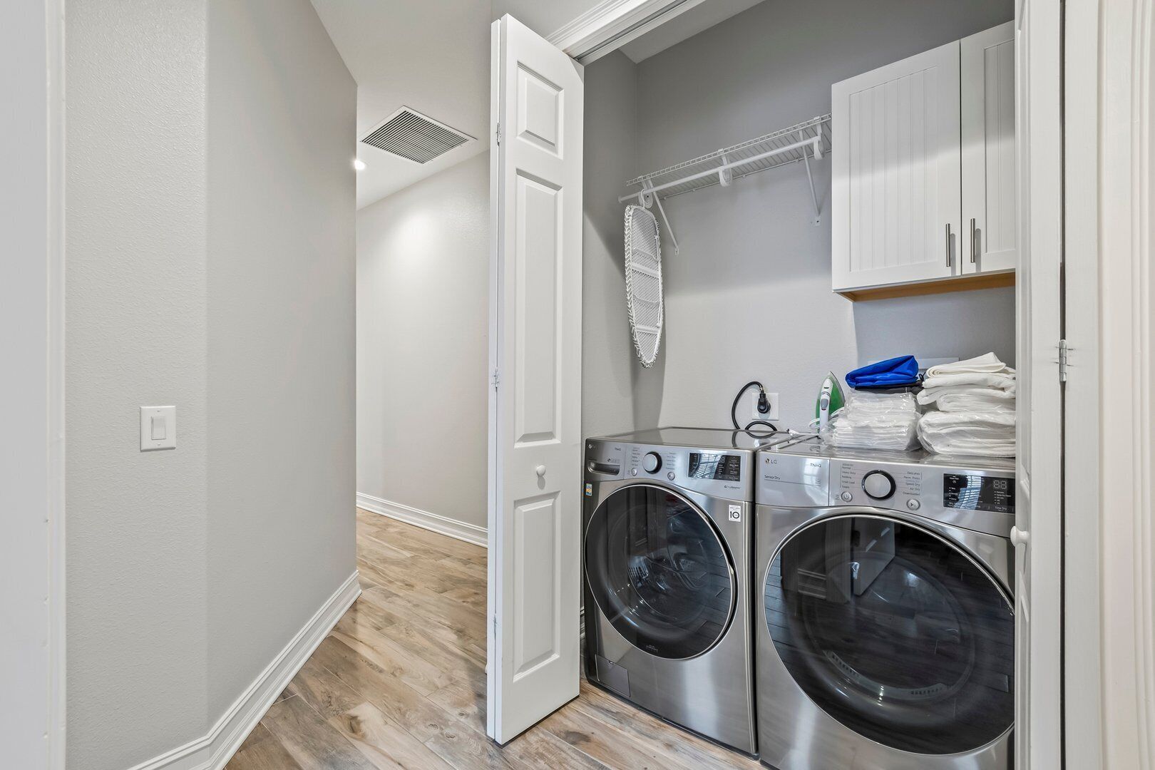 A laundry room with two front-loading washing machines, a drying rack, and a white door.