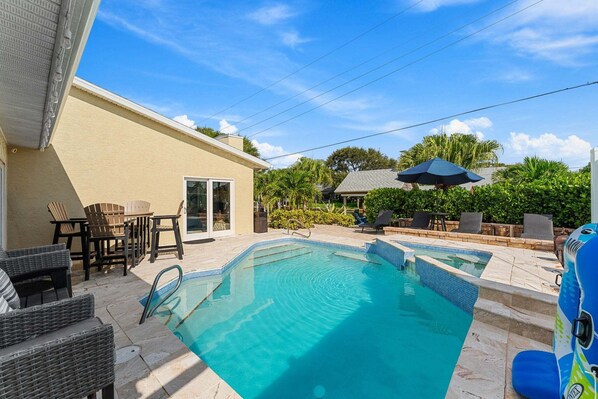 A backyard with a swimming pool, outdoor furniture, and a covered patio area. - 445 Watts Way (Cocoa Beach)