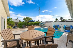 A backyard with a pool, outdoor furniture, and a tiki bar. - 445 Watts Way (Cocoa Beach)