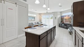 A modern kitchen with a central island, dark cabinetry, and pendant lighting. - 148 Mediterranean Way (Indian Harbour Beach)